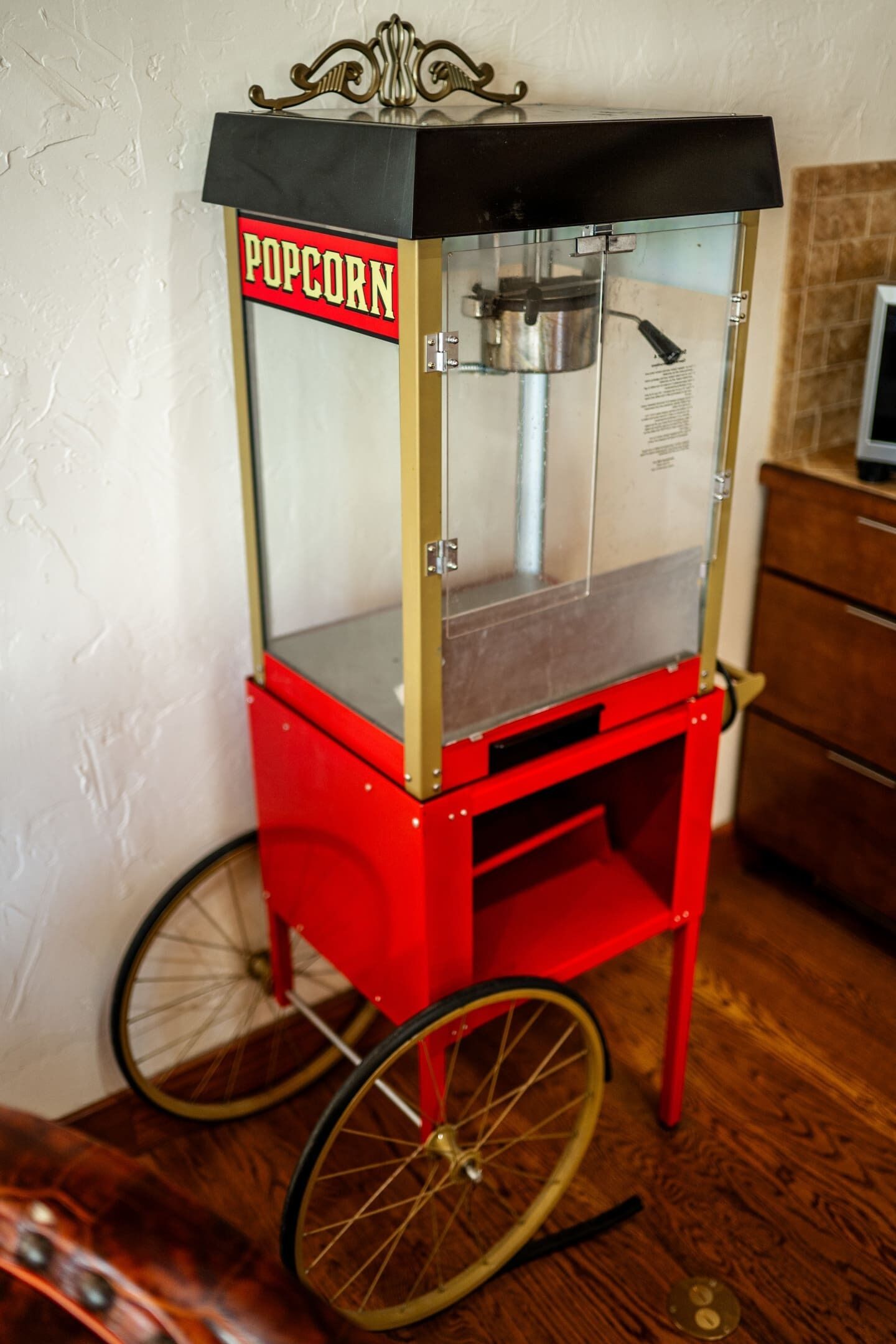 Una máquina expendedora de palomitas de maíz antigua con un letrero, montada sobre un carrito rojo con ruedas.
