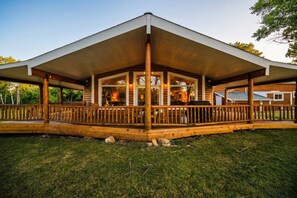 A wooden cabin with a covered porch and a large open area for outdoor activities. - Bunkhouse — Ranch Estate, Private Pond, Story WY (Banner)