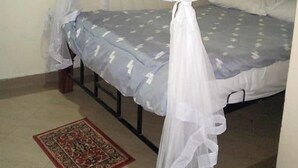 Un lit doté d’une moustiquaire, d’un tapis à motifs et d’un cadre de lit en métal.