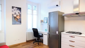 A compact kitchen with a refrigerator, stove, and a single chair. - Pordenone historic center (Pordenone)