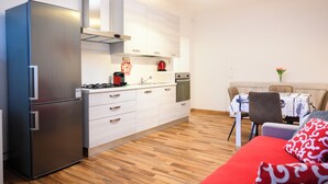 A compact kitchen with a refrigerator, stove, and modern cabinetry. - Pordenone historic center (Pordenone)