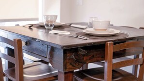 Una mesa de madera con un mantel individual blanco, un tazón y un vaso de agua.
