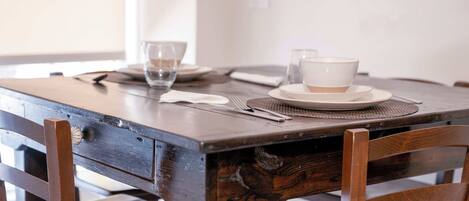 A wooden dining table with a white placemat, a bowl, and a glass of water.