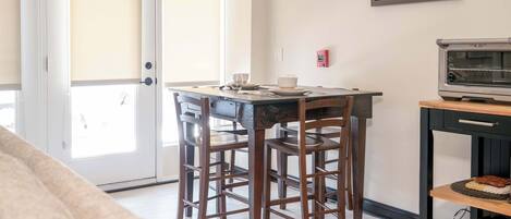 A dining area with a table, chairs, a coffee machine, and a map on the wall.