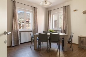 Ein Essbereich mit Tisch und Stühlen, einem Heizkörper und Blick auf Gebäude durch das Fenster.