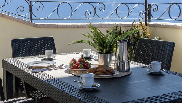 A table set for two with a view of the sea, a metal fence, and a potted plant. - Casa Marianna by Theater Home - located in the heart of Tignale with a marvellous lake view (Tignale)