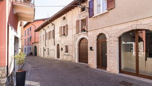 A narrow cobblestone street lined with historic buildings featuring arched doorways and wooden shutters. - Casa Marianna by Theater Home - located in the heart of Tignale with a marvellous lake view (Tignale)