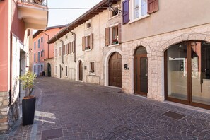Eine enge Kopfsteinpflastergasse gesäumt von historischen Gebäuden mit Rundbogenöffnungen und Holzfensterläden.