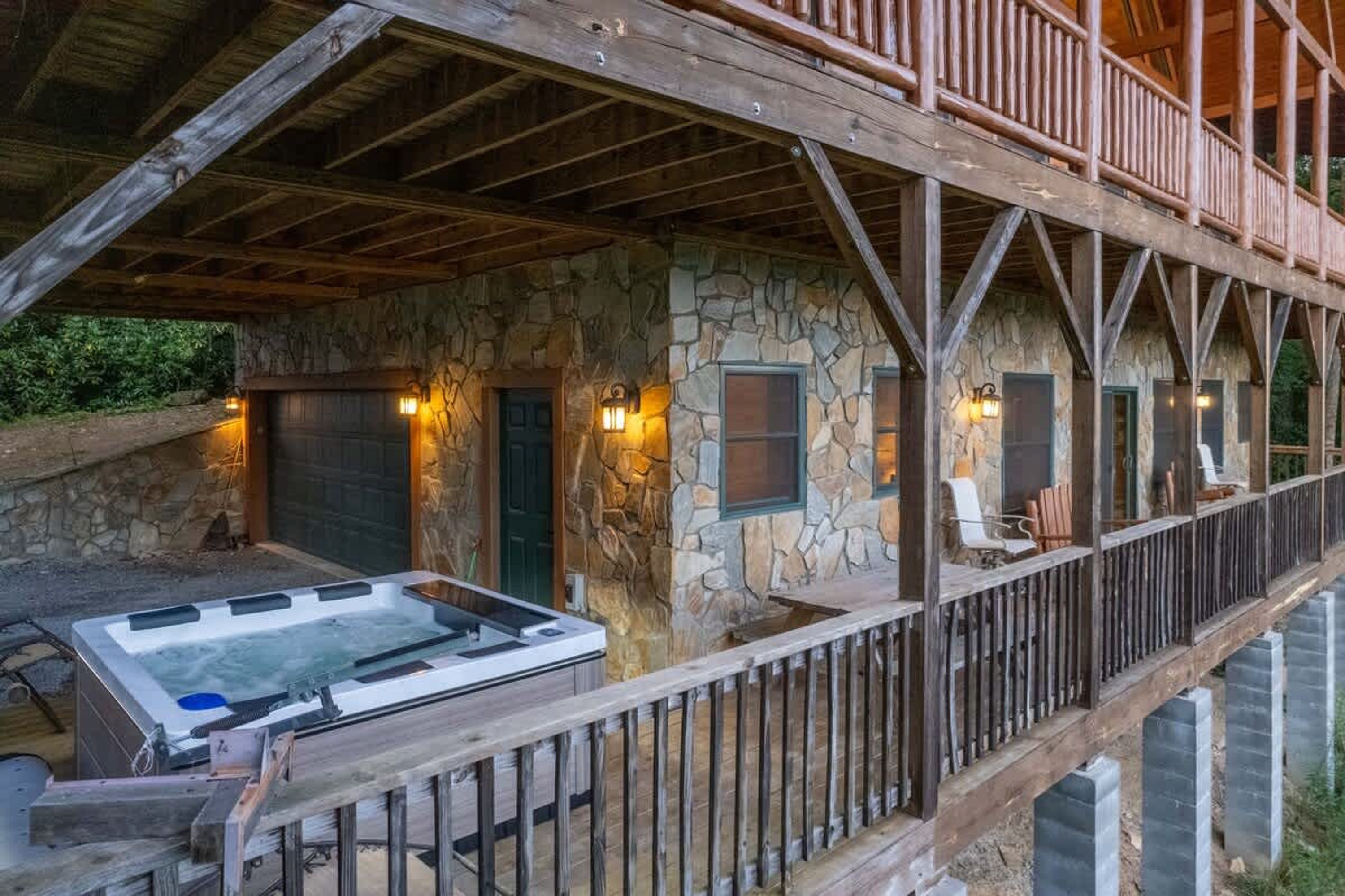 A stone building with a wooden deck, a hot tub, and a covered area with seating.