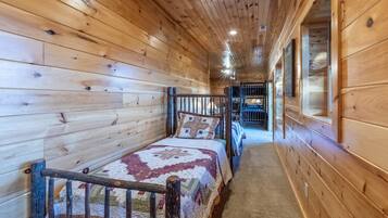Un pasillo estrecho con paredes de madera y una cama con colcha.