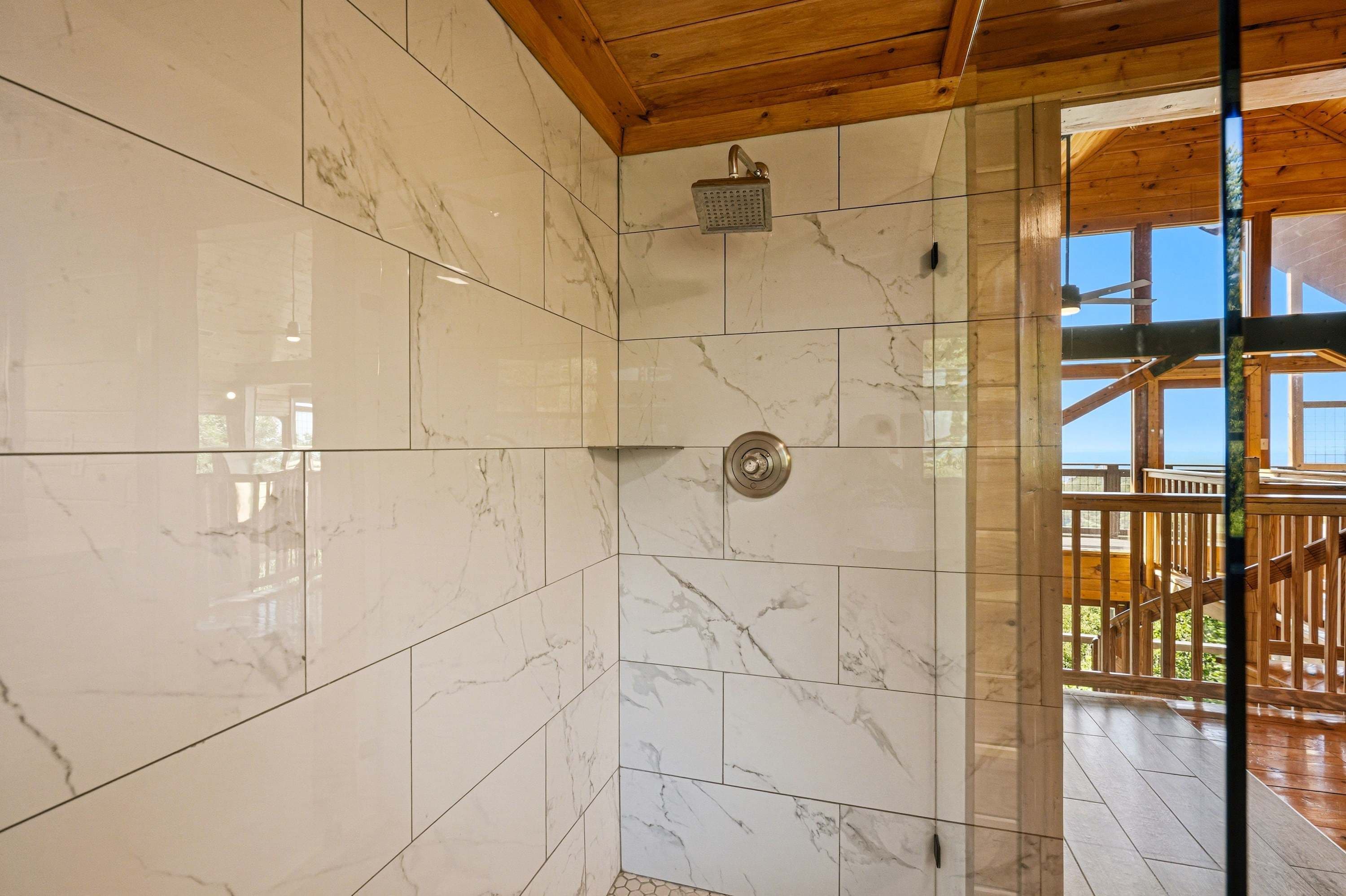 Un baño con baldosas de mármol, ducha y techo de madera.