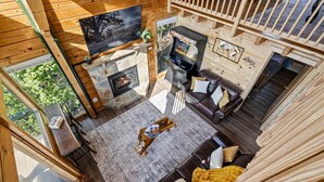 A cozy cabin interior with a stone fireplace, a gaming console, and a comfortable seating area. - Mountain Top Cabin With Views Hot Tub and Arcade (Sevierville)