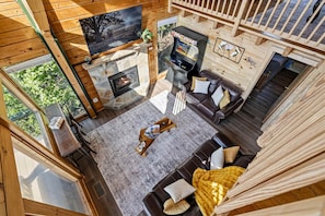 Ein gemütliches Blockhaus-Interieur mit Kamin, Spielekonsole und einer bequemen Sitzecke.