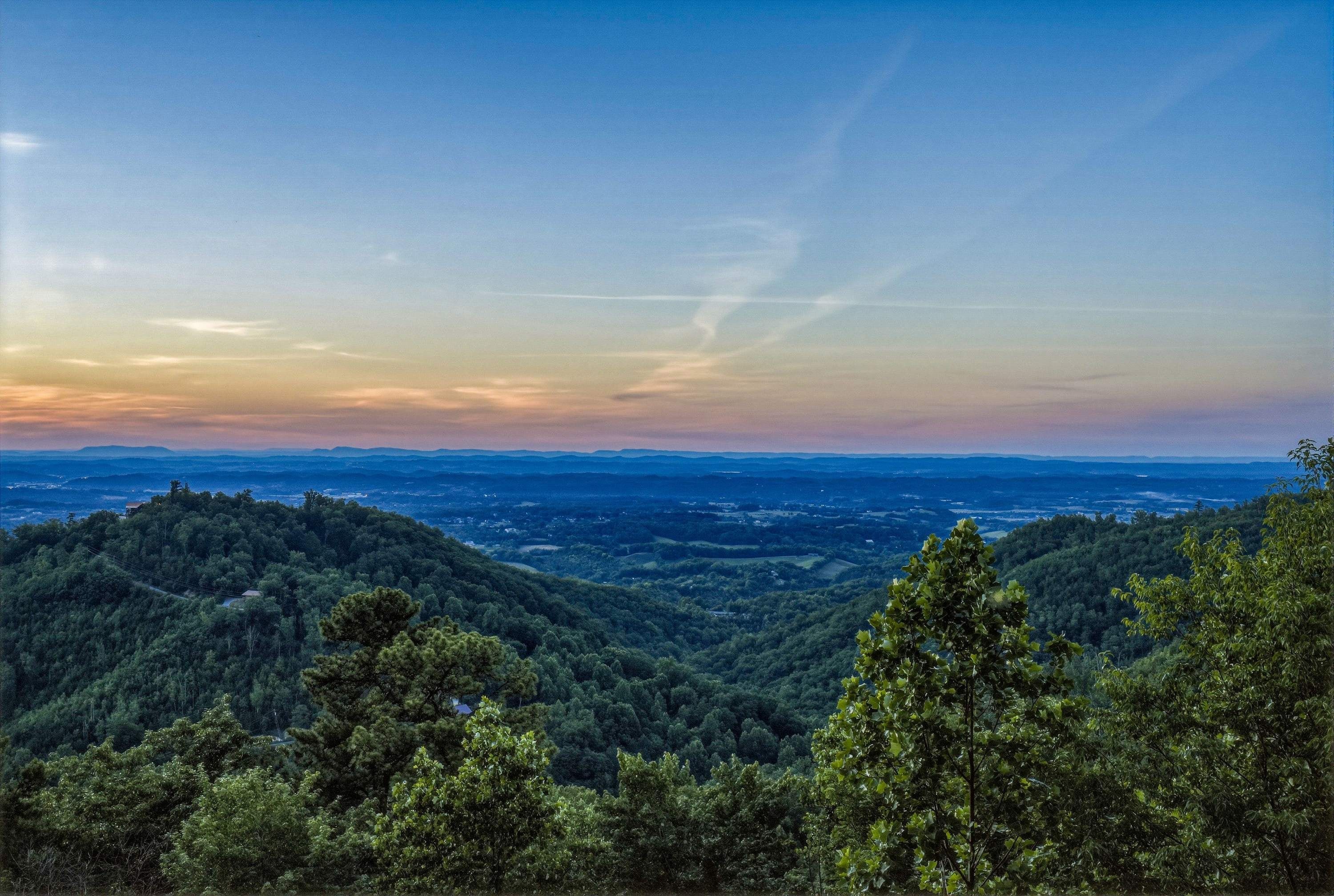 A mountainous landscape with dense forest coverage and a clear sky.