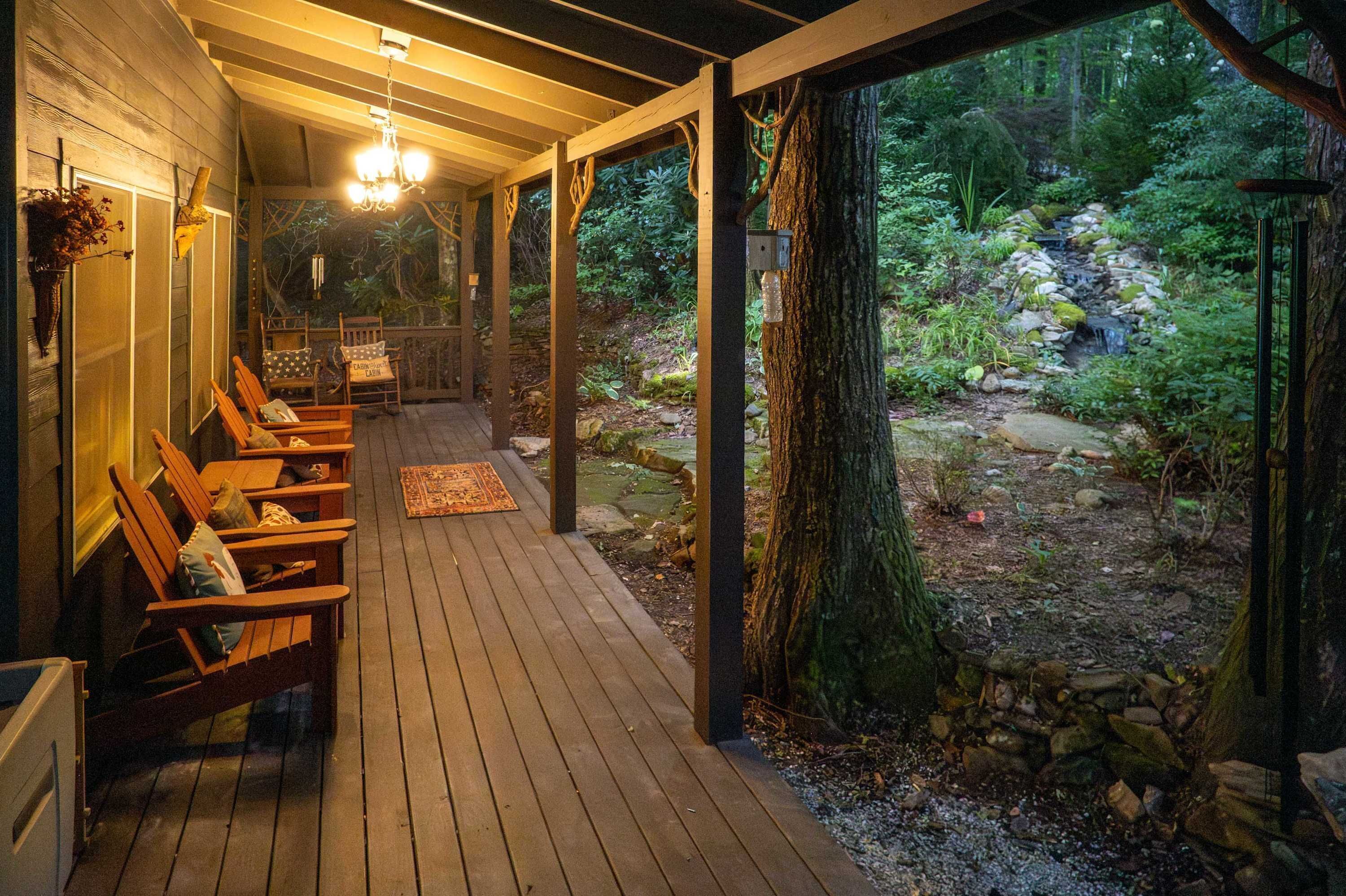Una terraza de madera con asientos, vista a un paisaje natural y una cascada.