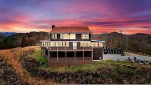 A two-story house with a large deck, surrounded by natural landscape and hills. - Secluded 7BR Mountain Escape on 7 Acres (Sevierville)