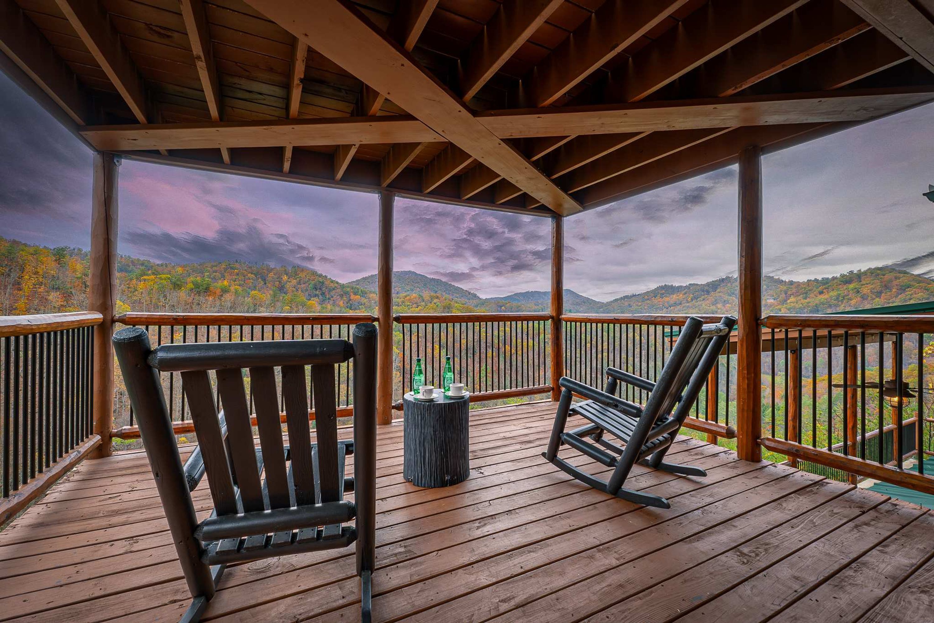 A wooden deck with two rocking chairs and a small table with bottles.