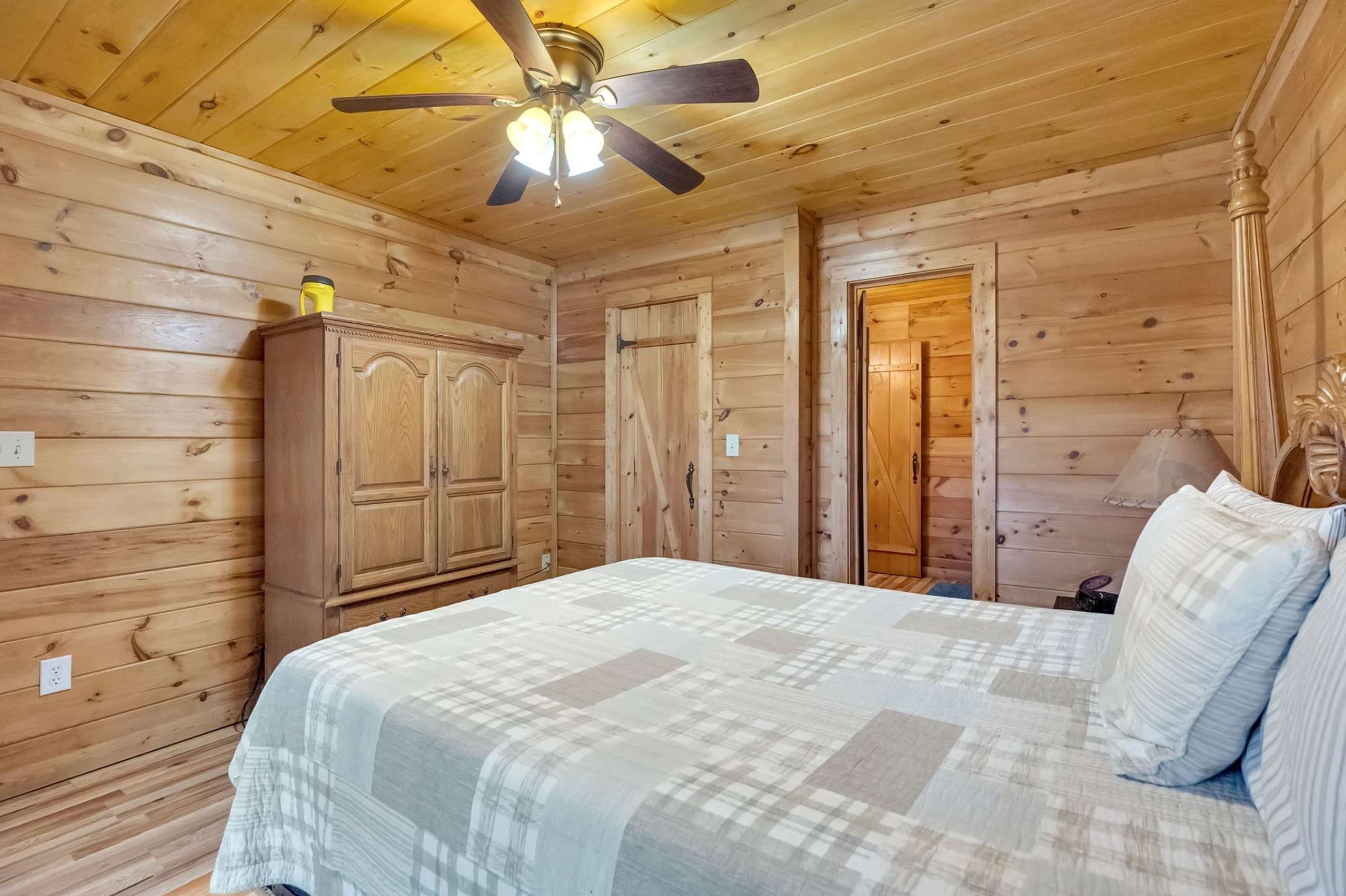 Um quarto com painéis de madeira, uma cama, um guarda-roupa e uma porta.