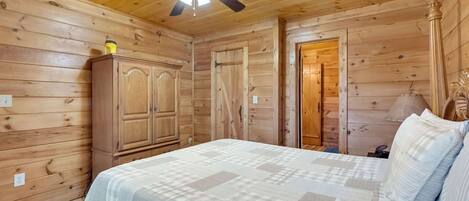 Um quarto com painéis de madeira, uma cama, um guarda-roupa e uma porta.
