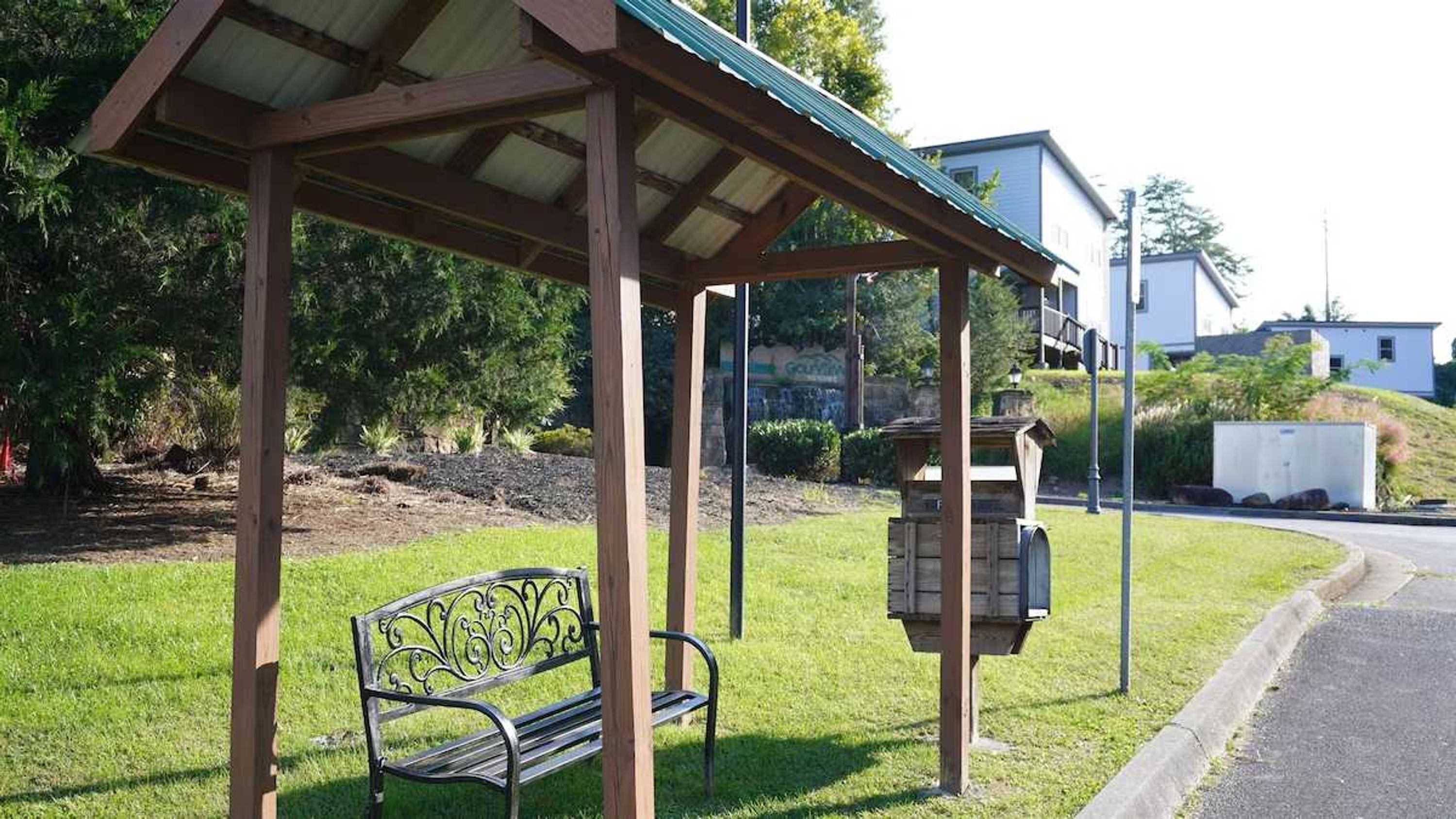 Un espace extérieur abrité, aménagé avec un banc et une boîte aux lettres.