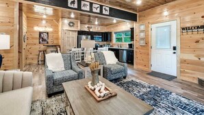 A cozy log cabin interior with a living room, kitchen, and dining area. - Modern 5 Bedroom Cabin Close-dollywood Game Room (Pigeon Forge)