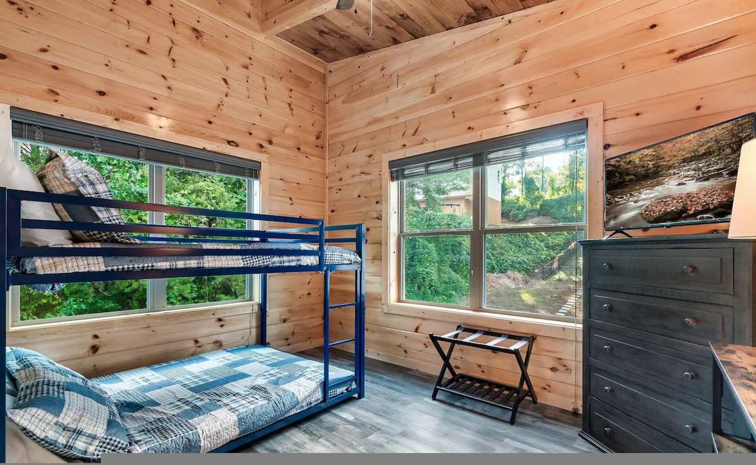 A wooden cabin room with bunk beds, a small table, and a dresser.