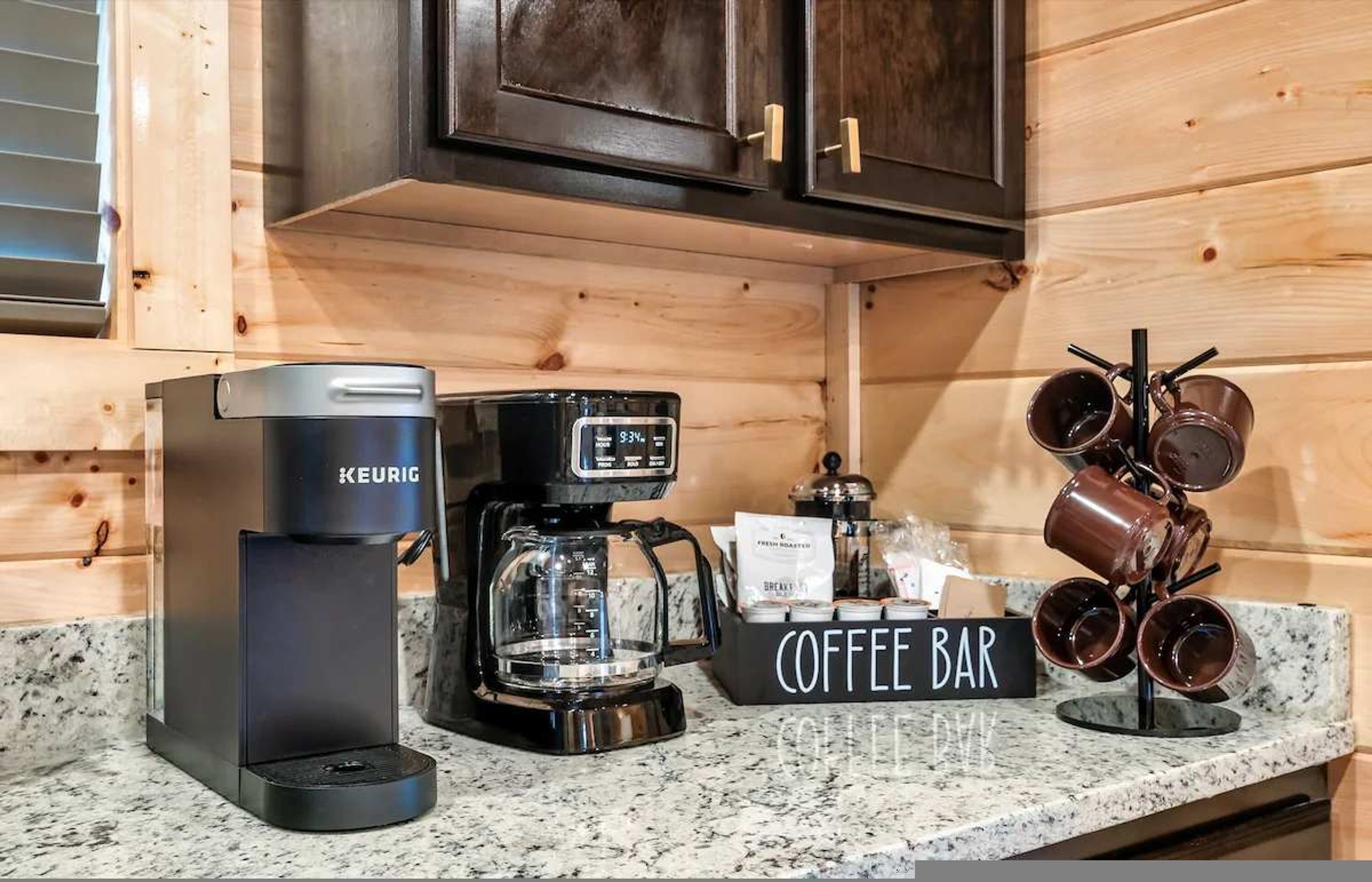 Una estación de café con una cafetera Keurig, un molinillo de café y un cartel que dice 'Coffee Bar'.