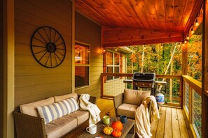 A wooden deck with a wicker sofa, a table with pumpkins, and a grill. - Stunning 4 King Suites Hot Tub Views Gamerm (Gatlinburg)