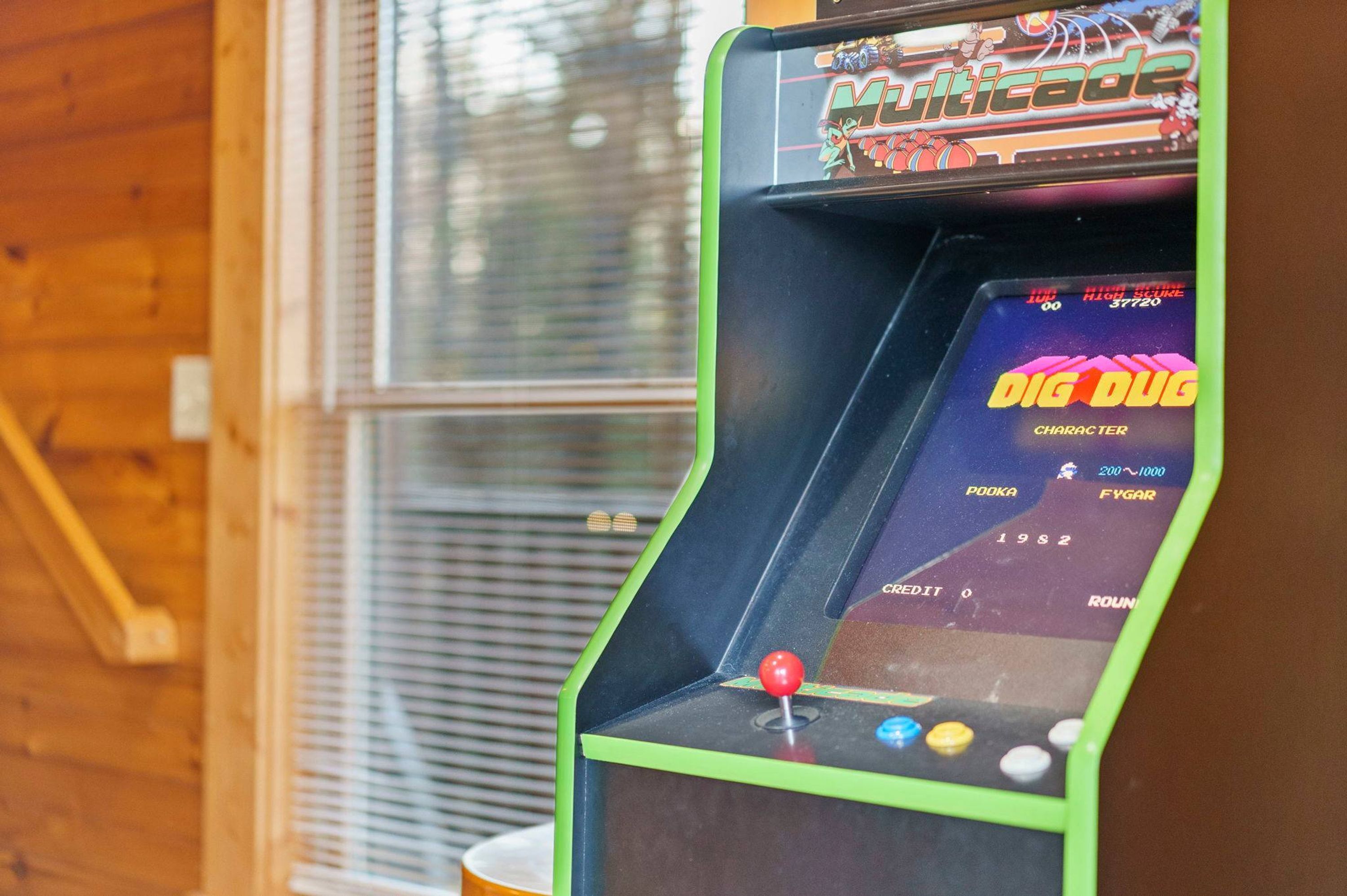 A vintage arcade game machine with a green frame and a screen displaying the game "Dig Dug".