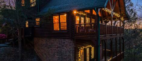 A log cabin with a balcony and string lights.