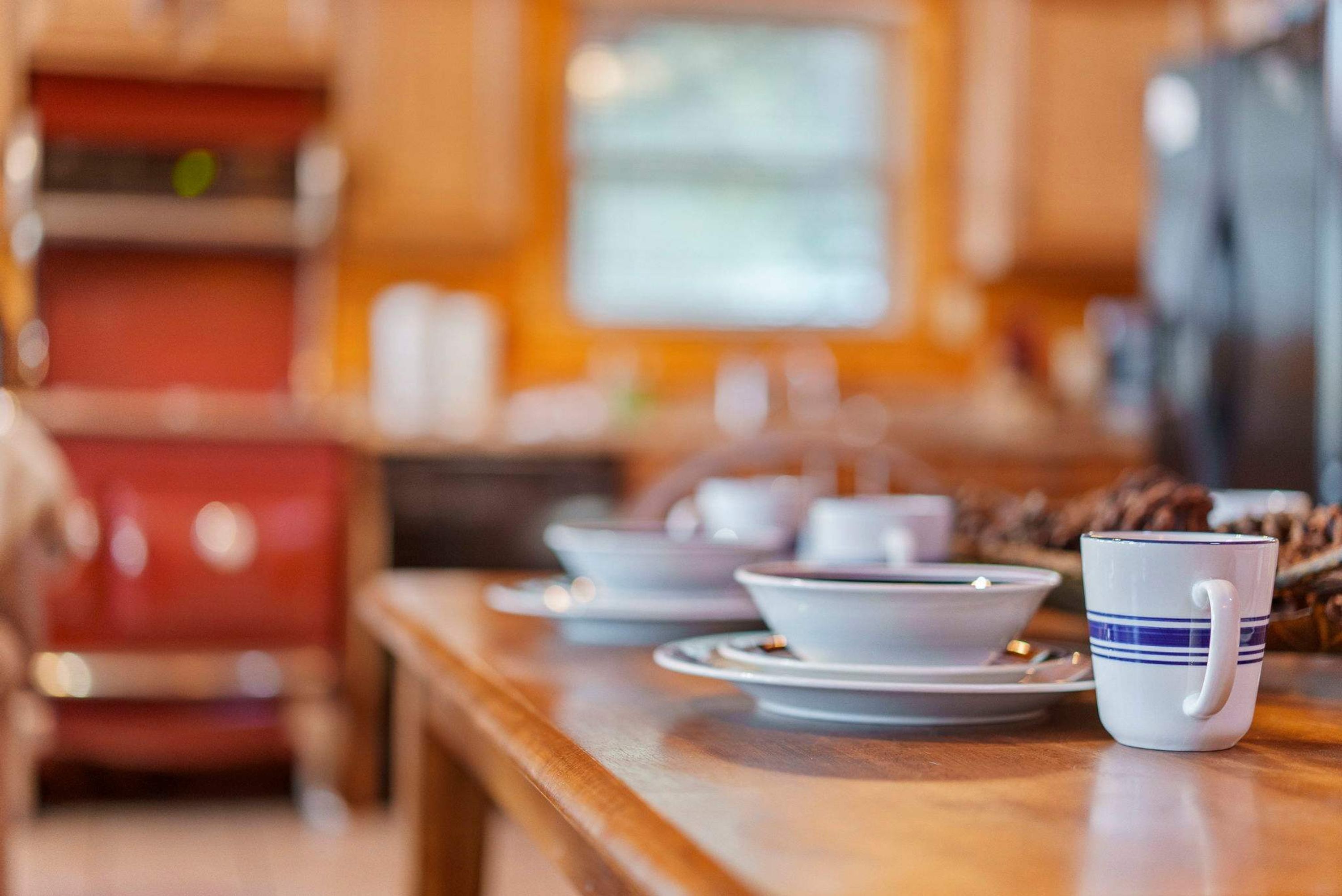 A dining table with white plates, bowls, and a blue-striped mug.