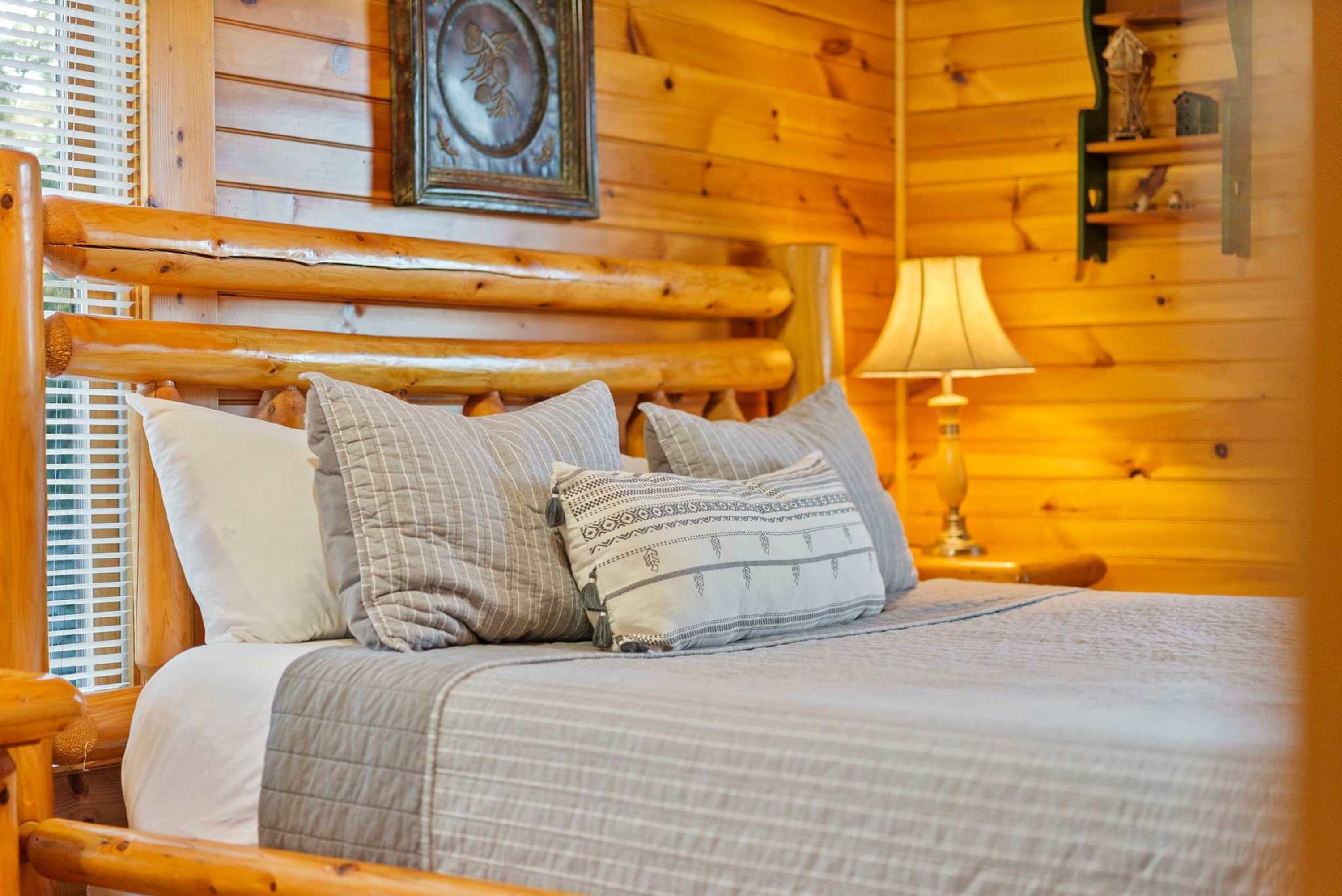 Una cama de madera con colcha acolchada y varias almohadas.