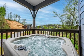 Een hottub op een houten terras, met uitzicht op een woonwijk en heuvels.