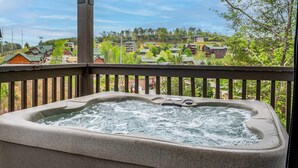A hot tub on a balcony with a view of a residential area. - Charming New 5BR 4BA Cabin Near Dollywood (Pigeon Forge)