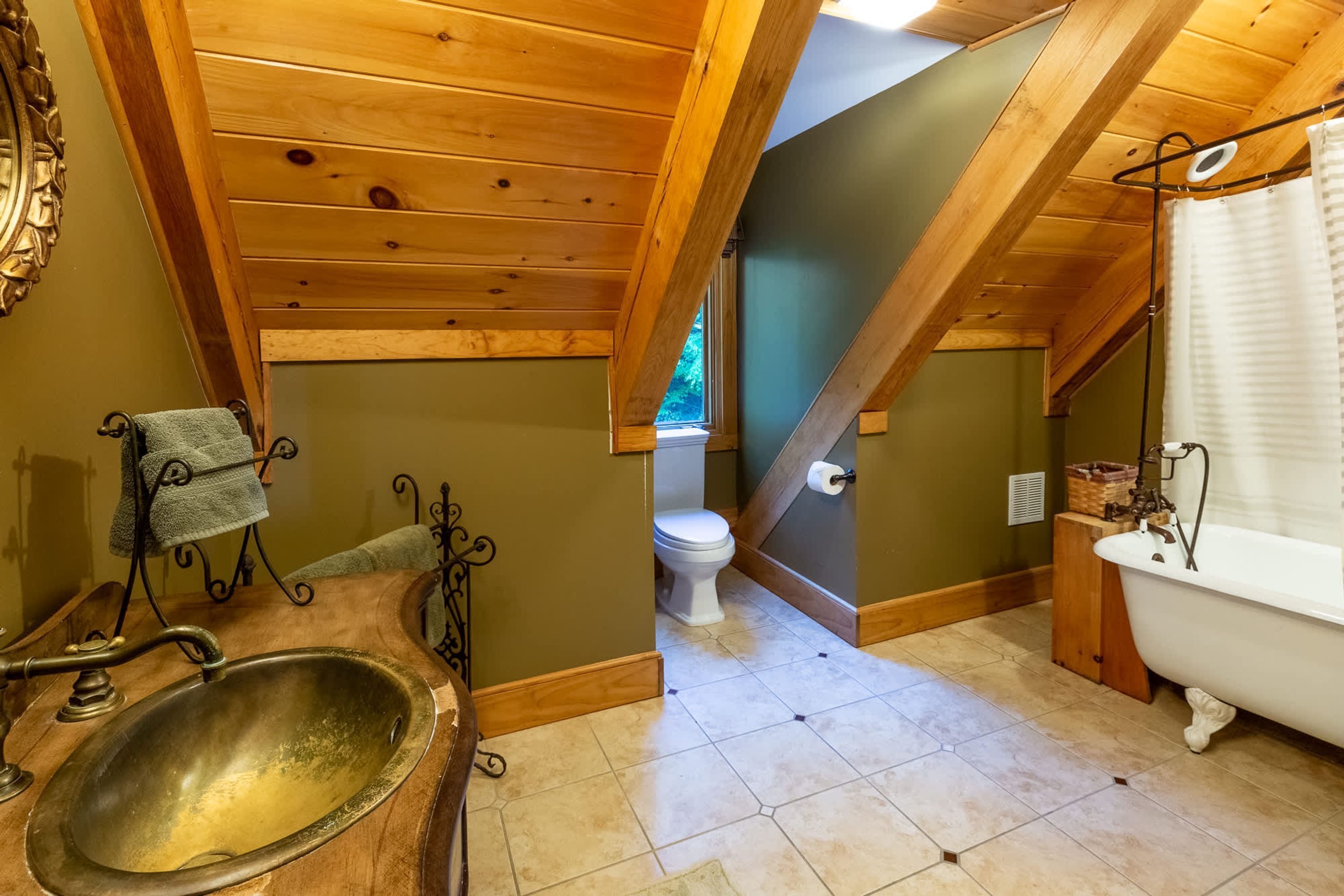 A bathroom with a wooden vanity, a freestanding bathtub, and a toilet.