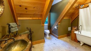 A bathroom with a wooden vanity, a freestanding bathtub, and a toilet.