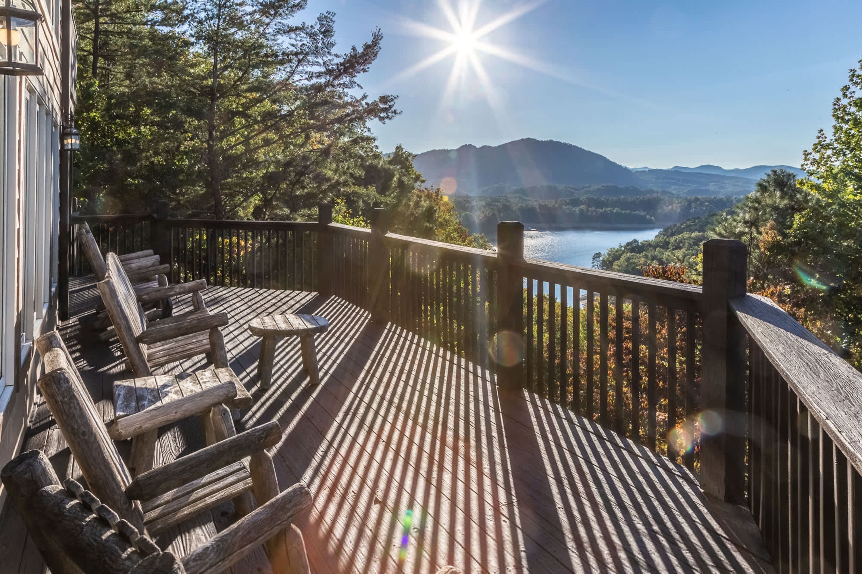 Una terraza de madera con vistas a un lago y montañas.