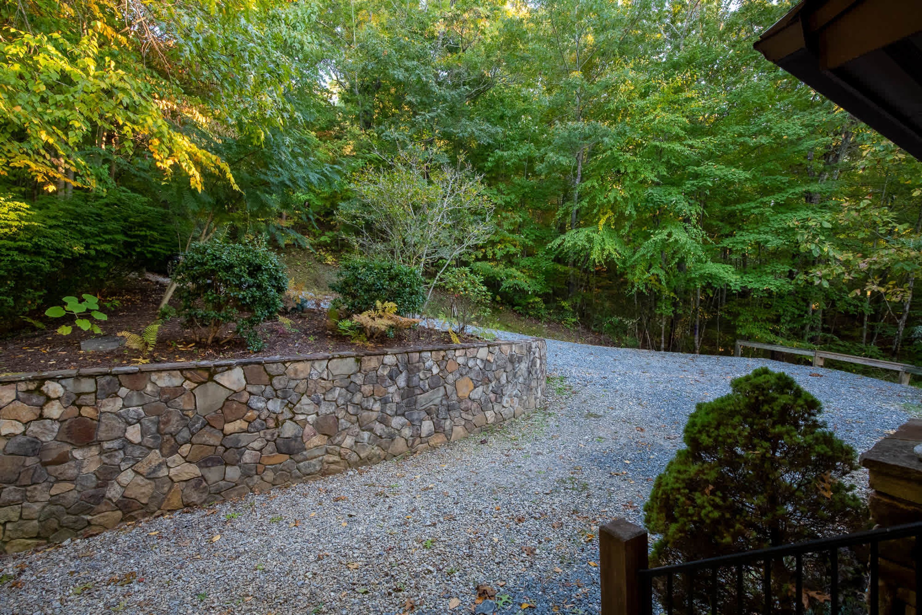 A stone retaining wall, a gravel path, and dense greenery.