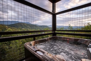 Ein Whirlpool mit Blick auf Berge und Grün hinter einem fensterartigen Gitter.
