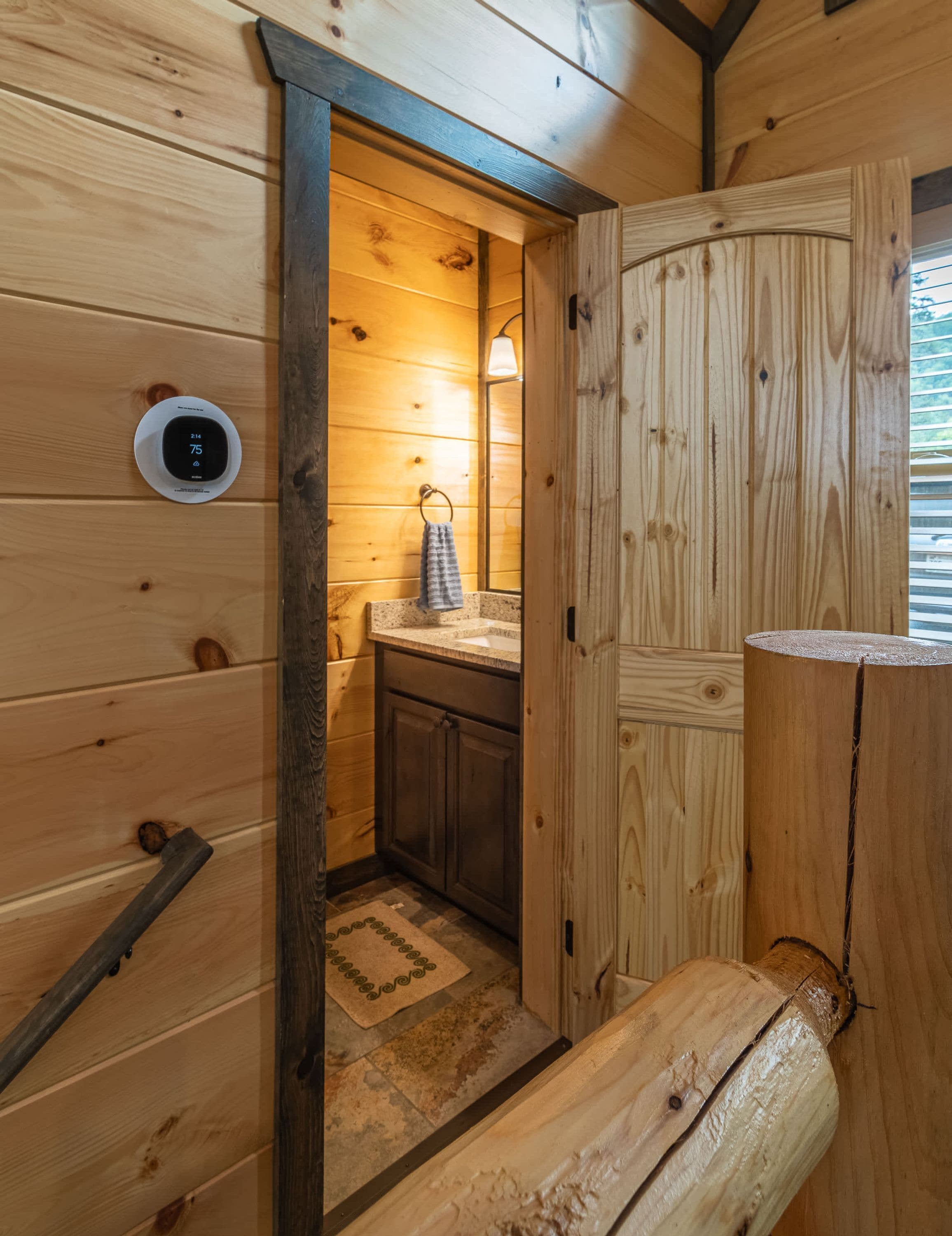 Une salle de bain rustique, avec des murs en bois, comprenant un banc en bois, un lavabo et un porte-serviettes.