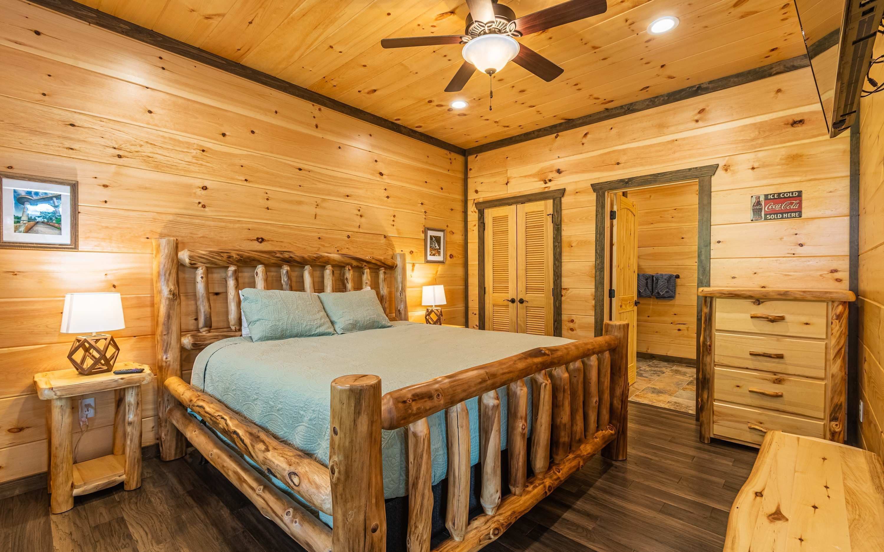 Une chambre dans une cabane en bois, comprenant un lit, des tables de chevet, un ventilateur de plafond et une armoire.