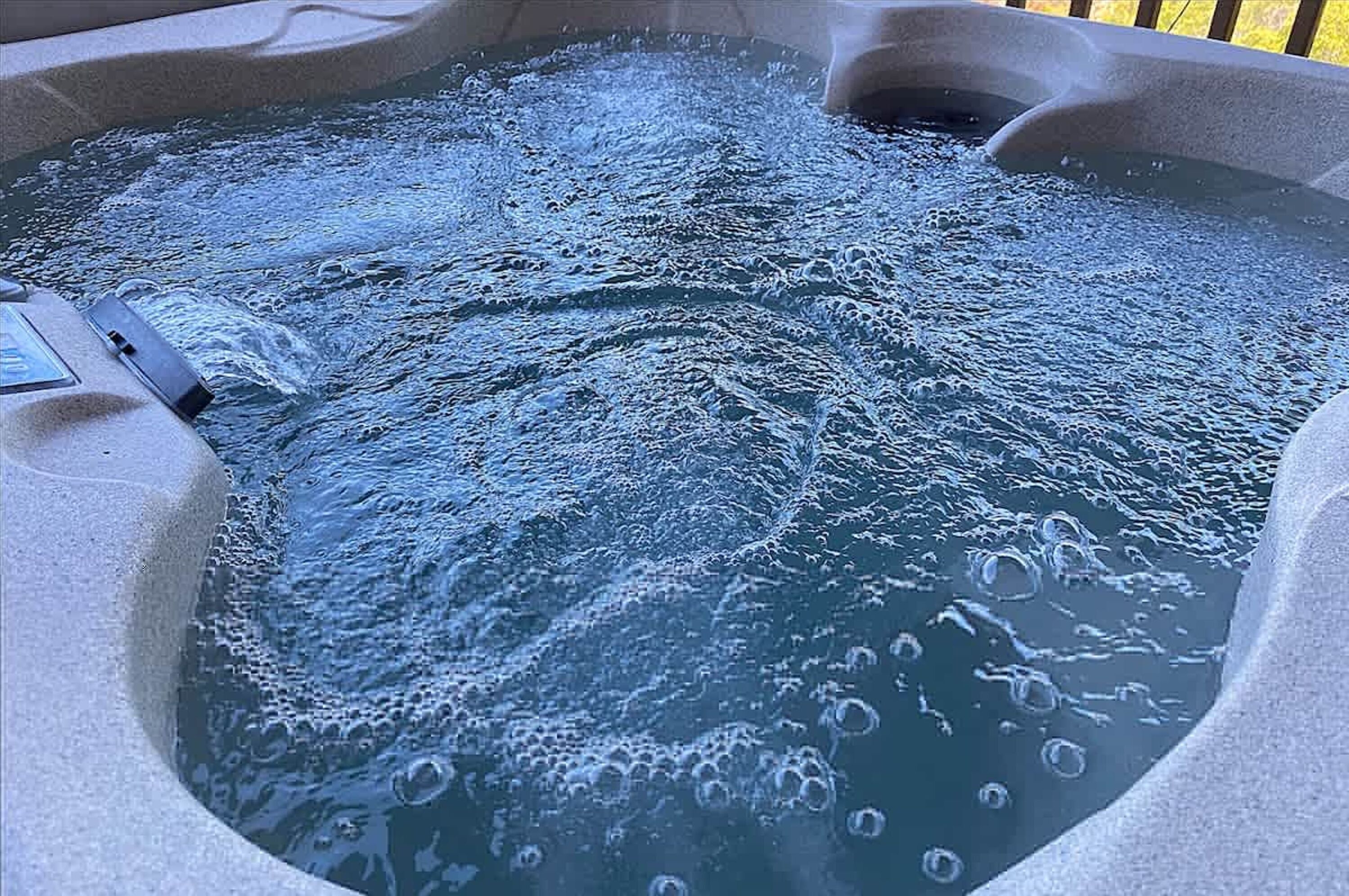 Una vasca idromassaggio con acqua frizzante e un pannello di controllo sul lato sinistro.