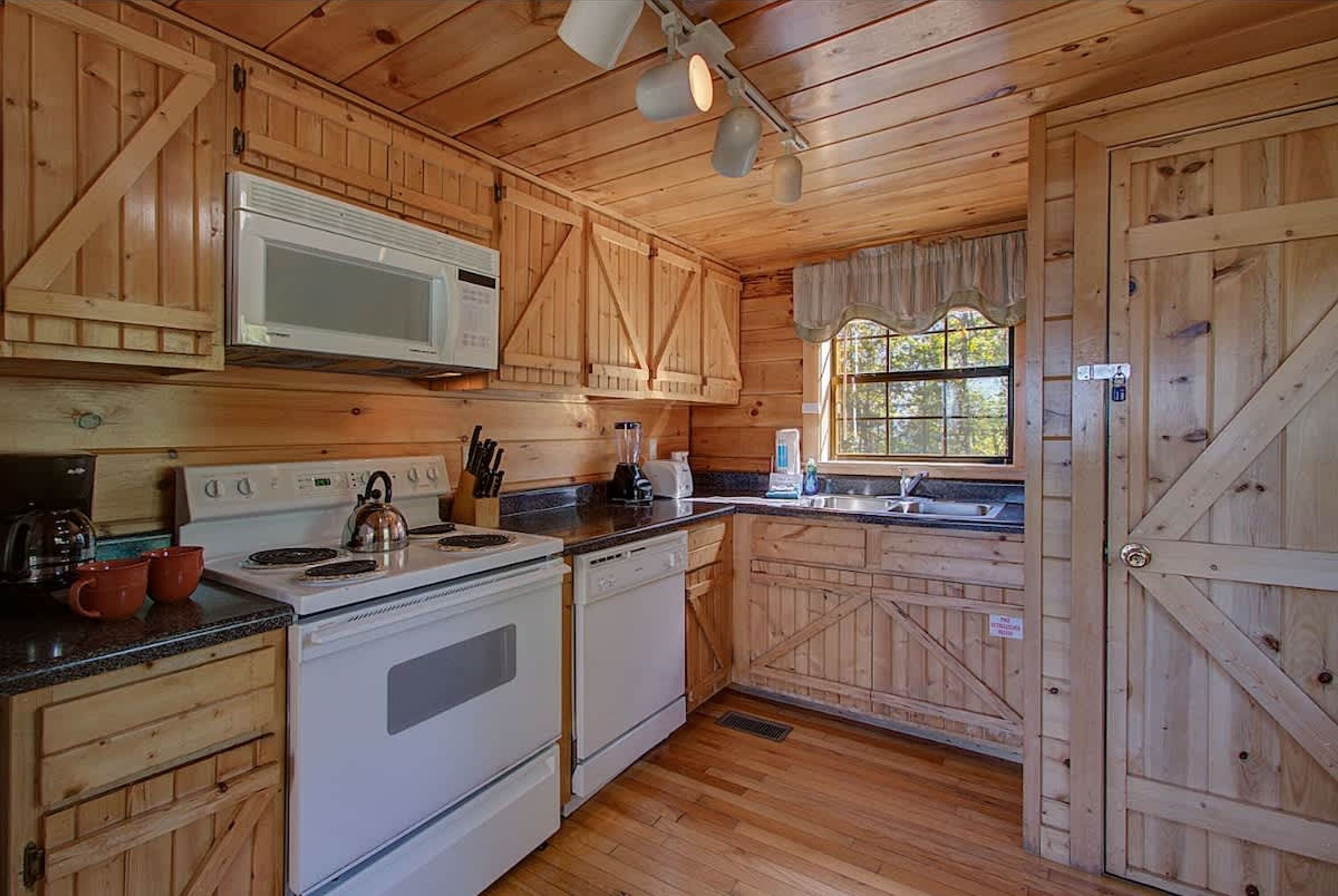 Cocina de cabaña de madera con microondas, estufa y lavaplatos.