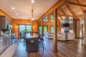 Una cocina amplia con una isla central, vigas de madera y una chimenea de piedra.