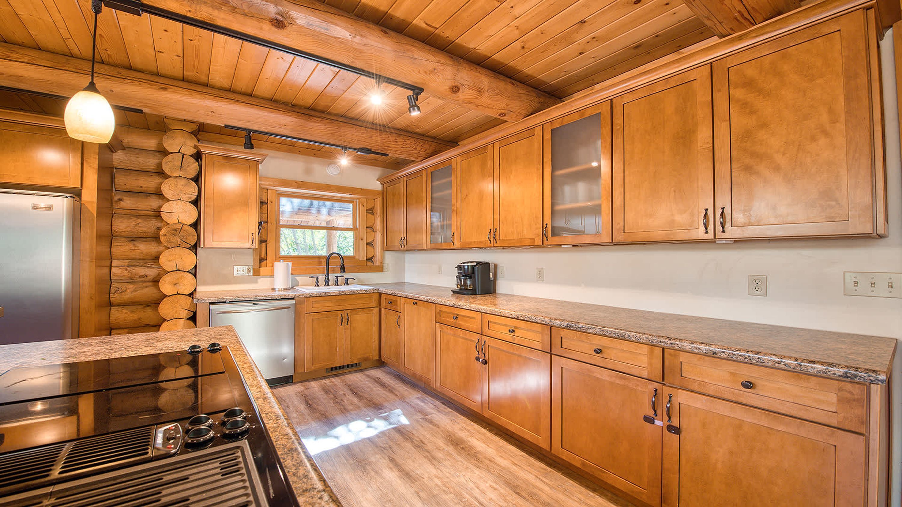 A kitchen with wooden cabinets, a stainless steel refrigerator, a stove, and a coffee maker.