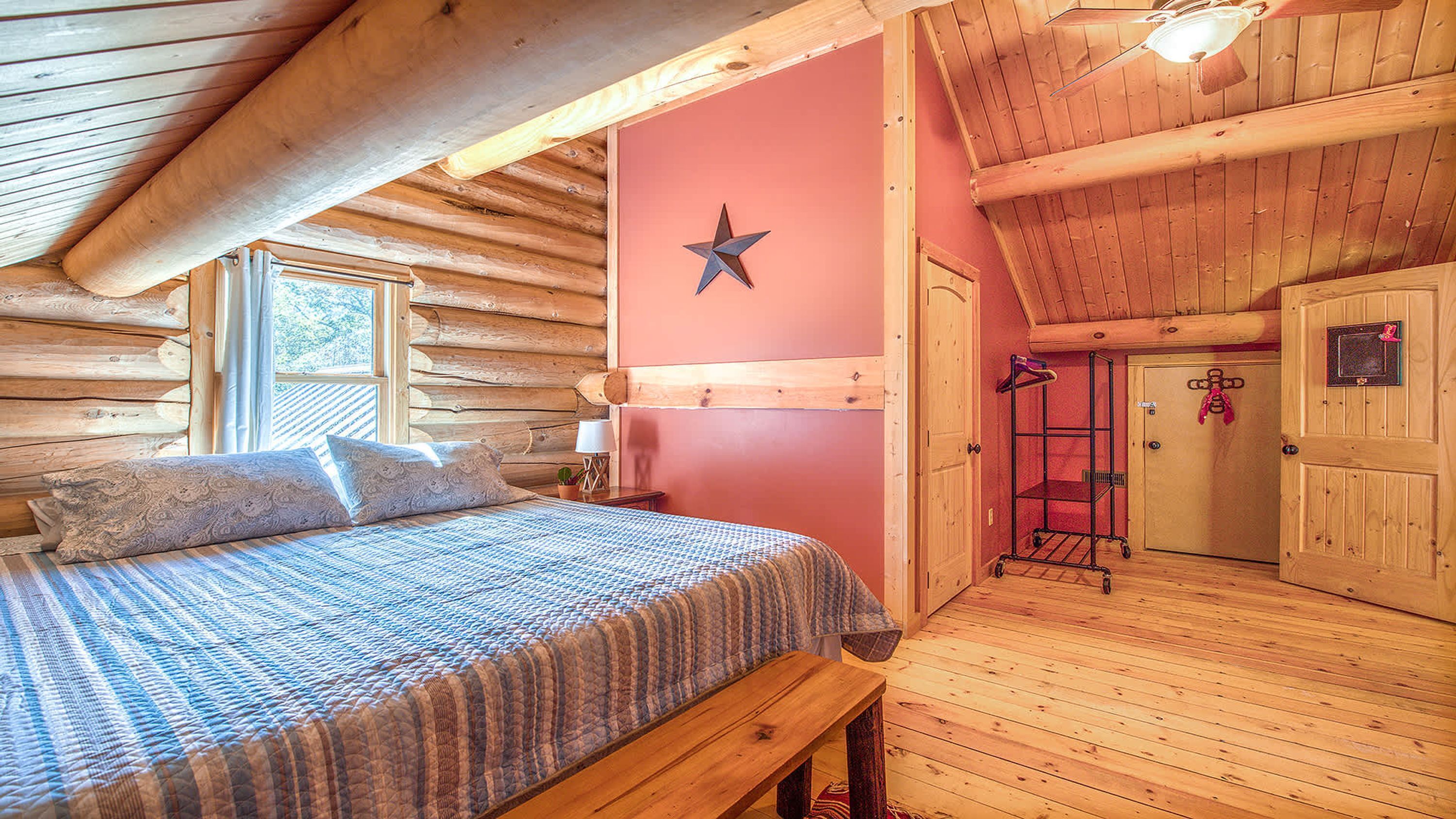 A log cabin bedroom with a bed, a star decoration on the wall, and a wooden bench.