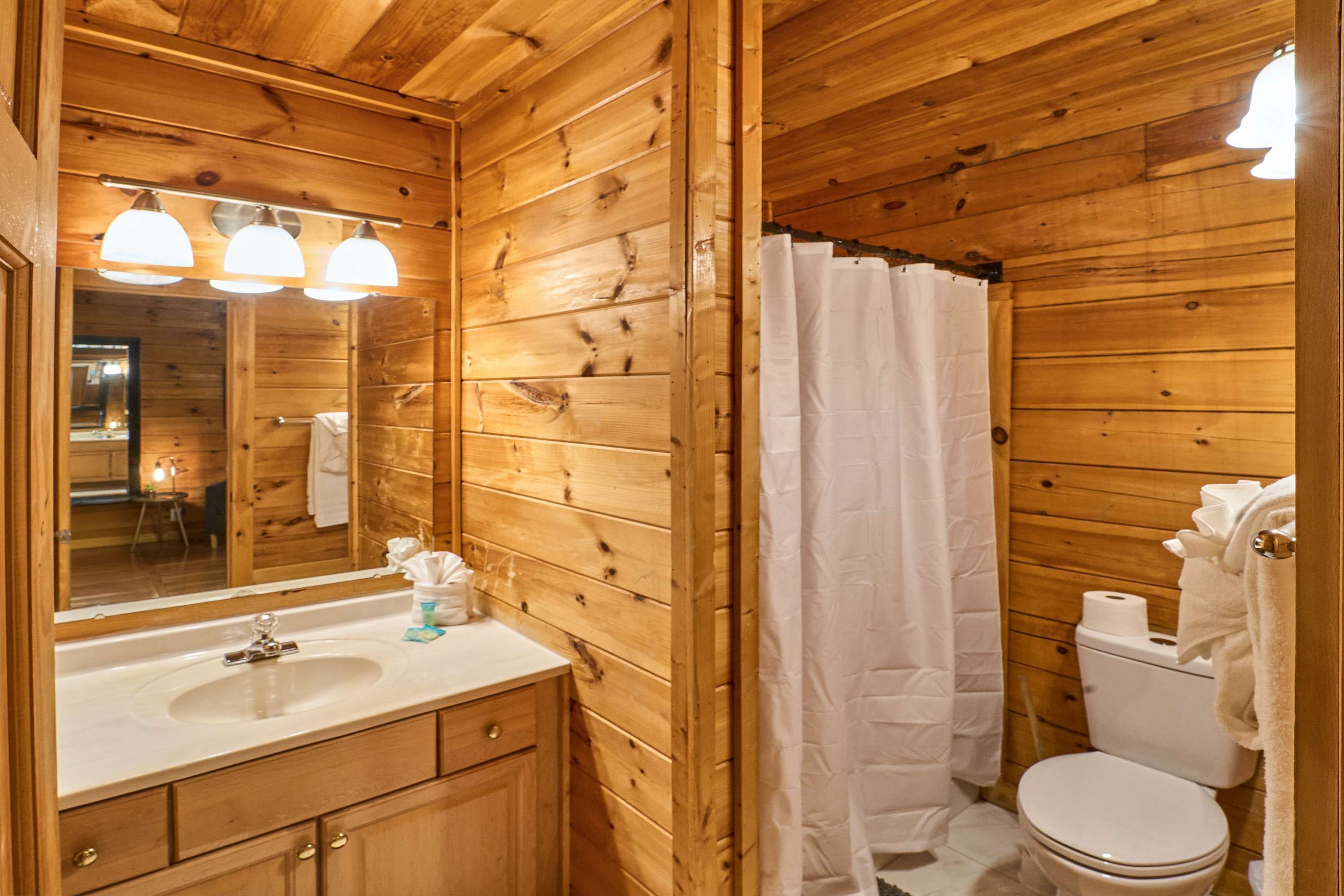 A wooden cabin bathroom with a sink, mirror, and toilet.