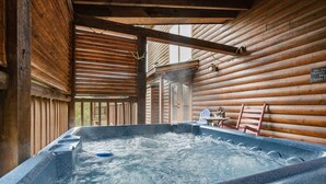 A hot tub in a log cabin with a wooden interior and a view of the outside. - 5BR Cabin w Yard Office Hot Tub Firepit (Sevierville)