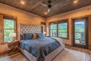 Ein Schlafzimmer mit einem großen Bett, Holzwänden und großen Fenstern mit Blick ins Freie.
