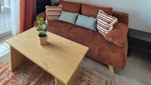 Een moderne woonkamer met een gestreepte bank, een houten salontafel en een potplant.